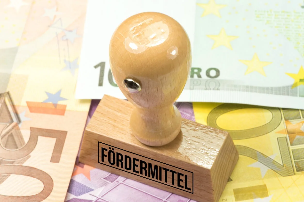 Ein Stempel mit der Aufschrift Fördermittel liegt auf mehreren Euroscheinen.