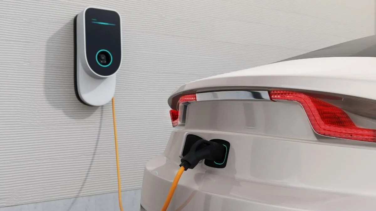 Eine Wallbox versorgt ein weißes Elektroauto in einer Garage mit Strom.
