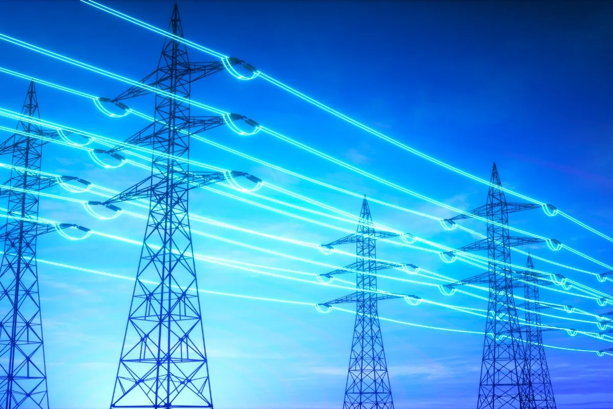 Glühende Stromleitungen an einem Mast symbolisieren die Aufgaben eines Netzbetreibers beim Transport von Energie.